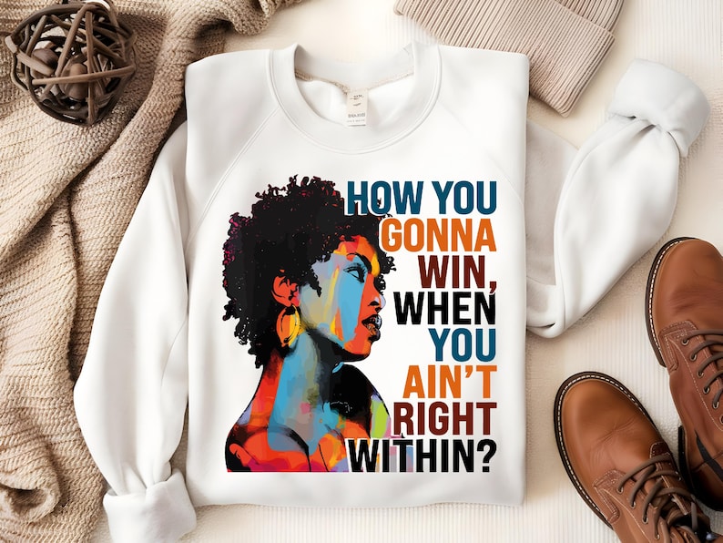 May include: White sweatshirt with a colorful illustration of a woman with an afro and the text "How you gonna win, when you ain't right within?"