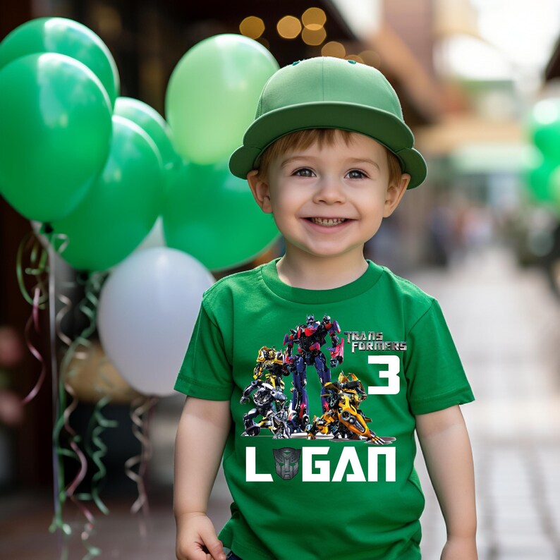 May include: Green t-shirt with a Transformers graphic and the number 3. The shirt also has the name Logan printed on it.