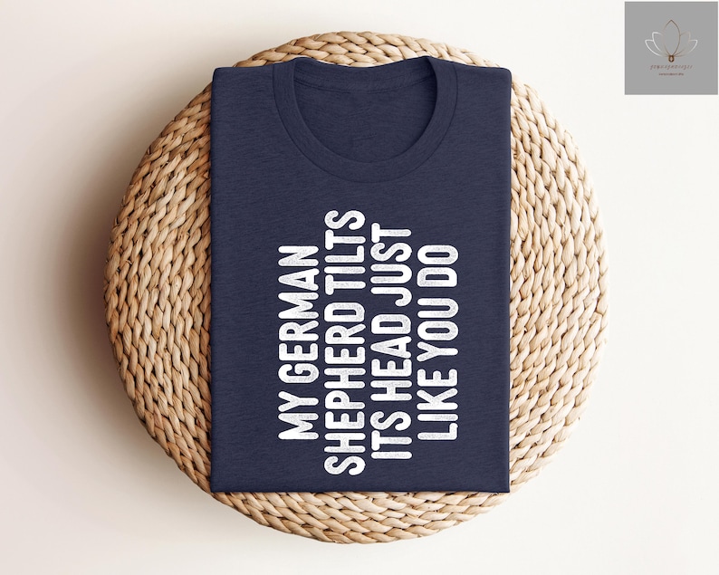 May include: A navy blue t-shirt with white text that reads "My German Shepherd Tilts Its Head Just Like You Do."