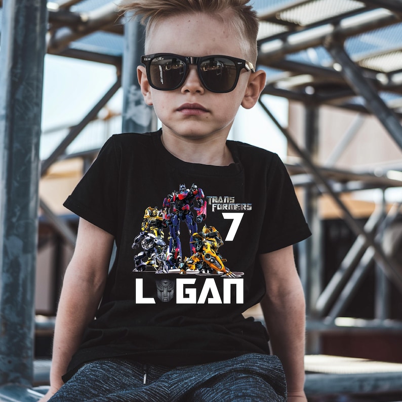 May include: Black t-shirt with a Transformers graphic, the number 7, and the name Logan printed in white.