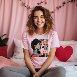 May include: A pink t-shirt with a colorful graphic of a woman's face and the text "How you gonna win when you ain't right within?"