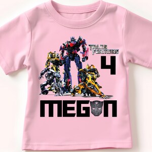 May include: Pink t-shirt with a Transformers graphic, the number 4, and the name Megan.