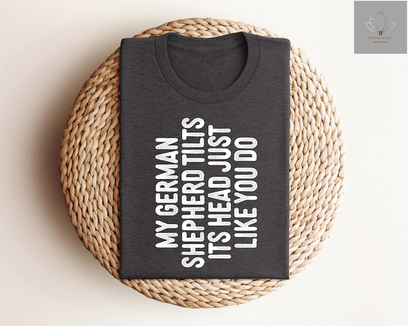 May include: A dark gray t-shirt with white text that reads "My German Shepherd Tilts Its Head Just Like You Do".