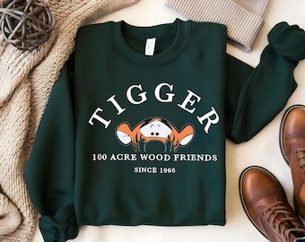 May include: A dark green sweatshirt with the words "TIGGER 100 ACRE WOOD FRIENDS SINCE 1966" printed in white. A cartoon image of Tigger is above the text.