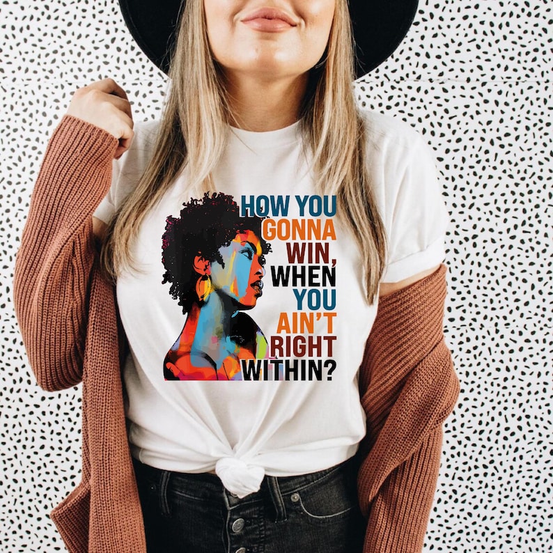 May include: White t-shirt with a colorful illustration of a woman and the text "How you gonna win, when you ain't right within?"