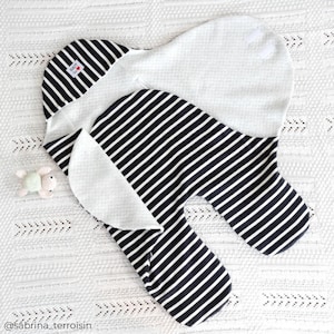 May include: A black and white striped swaddle with a white cotton lining. The swaddle is folded in half and has a small white tag with the word "Love" on it.