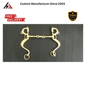 Può includere: Un morso per cavalli dorato con un cannone a snaffle e due pezzi laterali curvi. Il morso ha un design decorativo sui pezzi laterali.