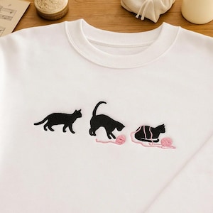 Cute Cat Yarn Embroidered Sweatshirt – Minimalist Black Cat Playing with Yarn, Gift for Cat Lovers, Cozy Embroidery Hoodie or T-Shirt