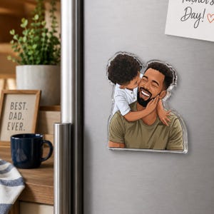 May include: A clear acrylic magnet featuring a cartoon illustration of a father being kissed on the cheek by a child. The father is wearing an olive green shirt and has a dark beard. The child is wearing a white shirt. The words "Best. Dad. Ever." are visible.