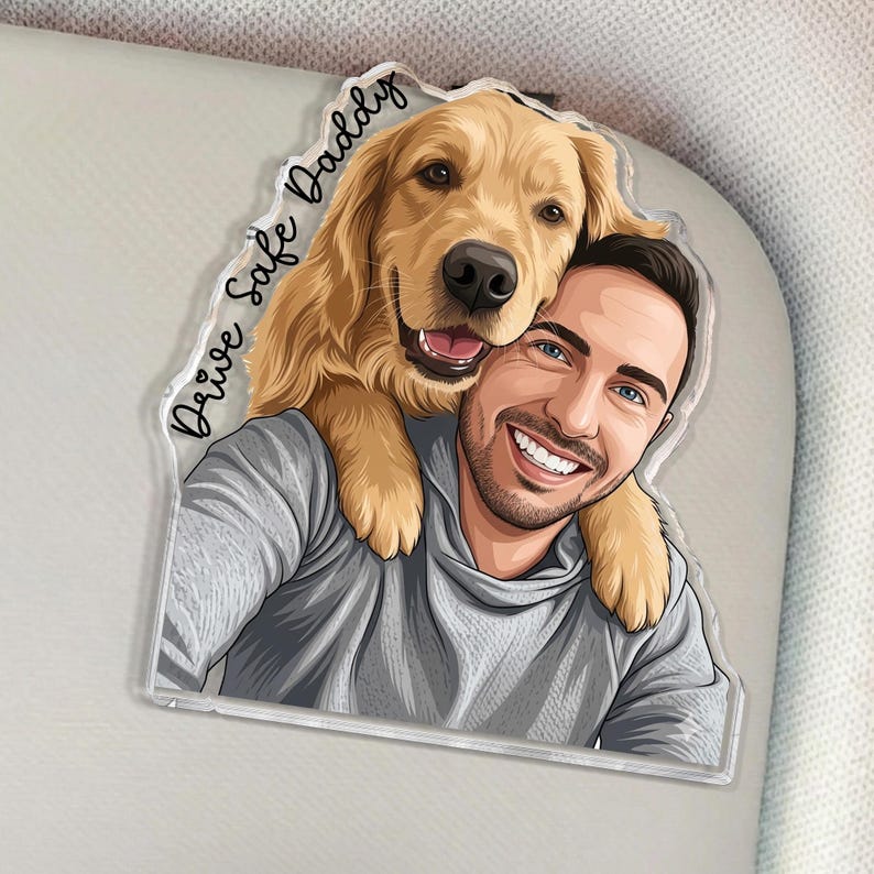 May include: A clear acrylic keychain featuring a smiling man and a golden retriever dog. The man is wearing a gray hoodie. The keychain has the text "Drive Safe Daddy" in a script font.