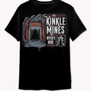May include: Black t-shirt featuring a graphic of a mine entrance with the text "KINKLE" above the entrance. The text "THE KINKLE MINES WITCH'S MINE" is printed on the right side of the shirt. The design includes a stylized illustration of a mine and a geometric symbol.