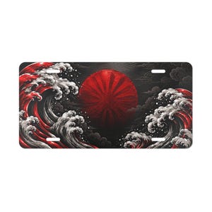May include: A rectangular number plate featuring a graphic illustration of a large, dark red sun with radiating lines centred against a black background, flanked by stylised, crashing waves in shades of red, white, and dark grey.