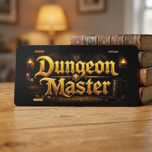 May include: Black license plate with the words "Dungeon Master" in gold lettering. The design includes candles, a mug, and a dragon. The plate is on a wooden surface.