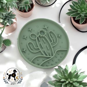 May include: A green silicone mold shaped like a cactus with stars and a crescent moon. The mold is on a white surface.