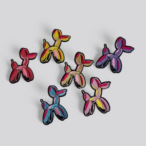 Może przedstawiać: Sześć kolorowych naszywek w kształcie balonowego psa z różnymi kombinacjami kolorów. Naszywki są wykonane z haftowanej tkaniny i mają czarny kontur.