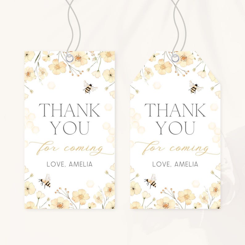 May include: Two white gift tags with floral and bee illustrations. The tags read "THANK YOU for coming, LOVE, AMELIA" in a mix of fonts. The tags are decorated with yellow flowers and bees, and have a string attached.