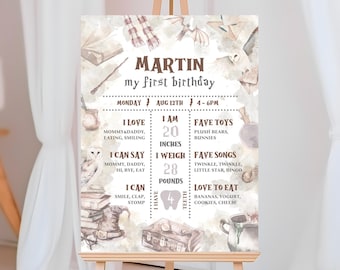 May include: A watercolor-style first birthday sign for a baby named Martin. The sign features a whimsical owl, a suitcase, a book, and a wand. It includes details like the baby's age, weight, and favorite things.