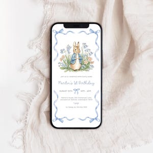 Op de afbeelding: Een smartphone toont een verjaardagsuitnodiging met een illustratie van een konijn in een blauw jasje, omringd door bloemen. De tekst luidt "Martin's 1e Verjaardag", met datum, tijd en adres, omlijst door blauwe linten.