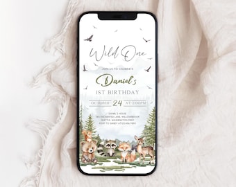 May include: A smartphone displays a birthday invitation with the text "Wild One" and "Daniel's 1st Birthday." The invitation features woodland animals, trees, and the date October 24 at 2:00 PM. The phone rests on a white, textured surface.