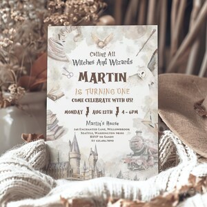 Könnte beinhalten: Eine Einladung im Vintage-Stil für eine erste Geburtstagsfeier mit Harry-Potter-Thema. Die Einladung zeigt eine Aquarell-Illustration von Hogwarts, einem Zug und anderen magischen Elementen. Der Text lautet "Calling All Witches And Wizards Martin Is Turning One Come Celebrate With Us! Monday Aug 12th 4-6PM Martin's House 345 Enchanted Lane, Willowbrook Seattle, Washington 98101 RSVP to Sandy At 123.456.7890"