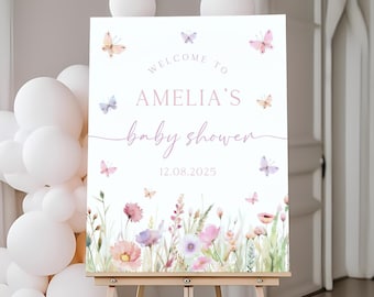 Puede incluir: Bienvenido a la baby shower de Amelia, cartel con diseño floral de acuarela y mariposas. El cartel es blanco con texto rosa y la fecha 12.08.2025.