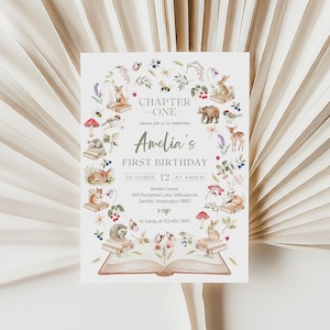 May include: A white birthday invitation card featuring a woodland theme with illustrations of animals and flowers. The text reads "Chapter One" and "Amelia's First Birthday, October 12 at 4:00 PM". Includes RSVP details and address.