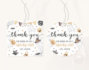 Può includere: Due etichette regalo a tema Halloween, una quadrata e una rotonda, con sfondo bianco. Le etichette presentano fantasmi, zucche, pipistrelli e ragni. Il testo sulle etichette recita "grazie" e "per aver reso la mia giornata spettrale!" con il nome "Jackson".