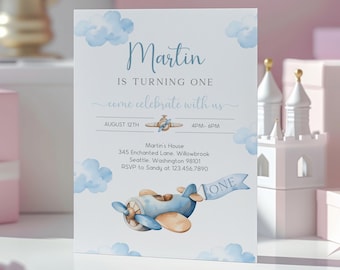 May include: Blue and white airplane birthday invitation with the text "Martin is turning one, come celebrate with us, August 12th, 4PM-6PM, Martin's House, 345 Enchanted Lane, Willowbrook, Seattle, Washington 98101, RSVP to Sandy at 123.456.7890".