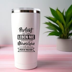 May include: A white stainless steel tumbler with a silver rim and lid. The tumbler features black text that reads "Perfekt ist das Leben nie, aber es gibt Menschen die es perfekt machen."