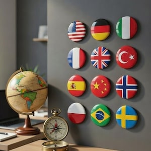 Può includere: Una collezione di magneti rotondi con le bandiere di vari paesi, tra cui Stati Uniti, Germania e Italia, è esposta su una parete grigia. Un mappamondo vintage e una bussola sono su una scrivania di legno.