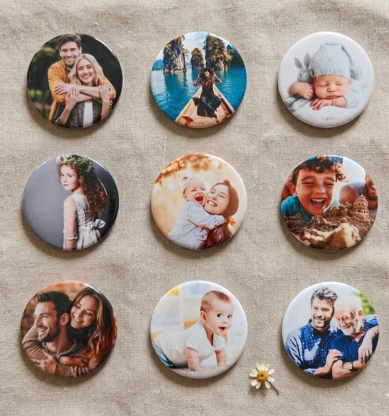 May include: A set of nine circular photo badges featuring various printed images, including couples, a person in a boat, a baby in a hat, a child with a flower crown, a parent and child, a child playing in sand, and two pairs of men.