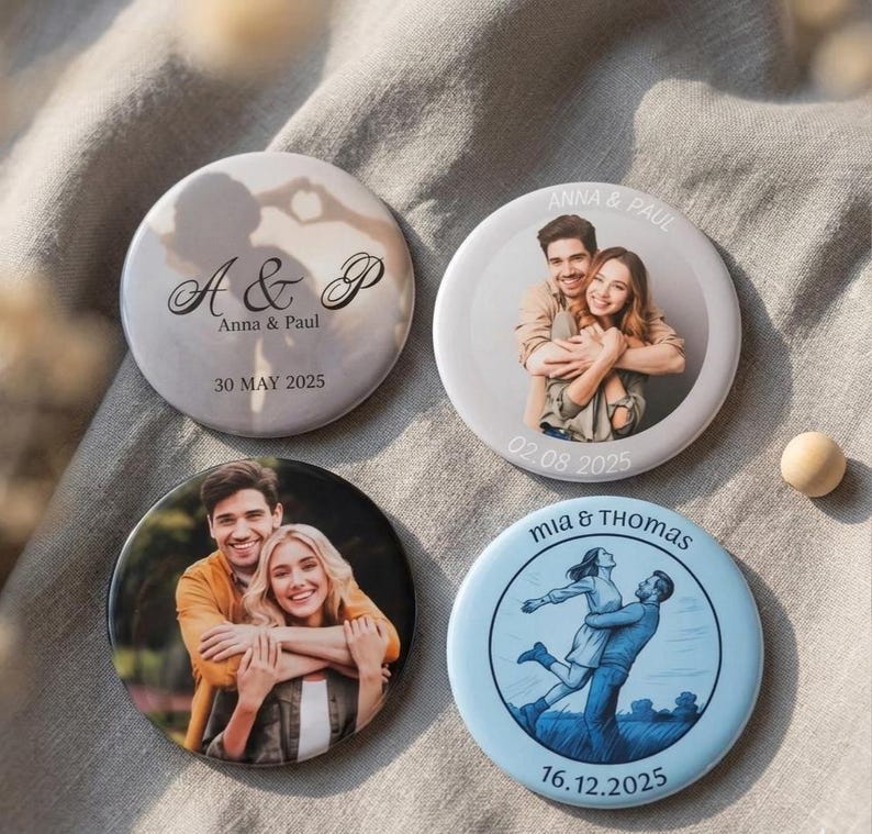 May include: Four circular custom pin-back buttons featuring personalised designs. Two buttons display photographic portraits of couples, one shows a silhouette with the text A & P Anna & Paul 30 MAY 2025, and one features a blue illustration of a couple.