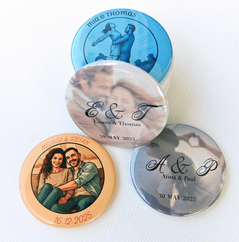 May include: Four circular pin-back buttons featuring personalised designs. One shows a blue illustration of a couple with the text Mia & Thomas. Another displays a photo of a couple with E & T, Emma & Thomas, and 30 May 2025. A third shows a couple with Melissa & Stefan and 16.12.2025. The last shows A & P, Anna & Paul, and 30 May 2025.