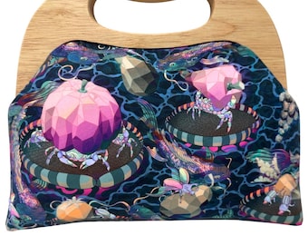 May include: A unique handbag with a wooden handle. The bag features a colorful, patterned design with geometric shapes, fish, and crabs on a dark blue background. The handle is made of light-colored wood.