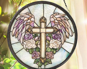 May include: Round stained glass window art featuring a cross, angel wings, and roses. The cross is centered, surrounded by white and purple roses. The wings are in shades of purple and tan. The window is framed in black and hangs from a chain.