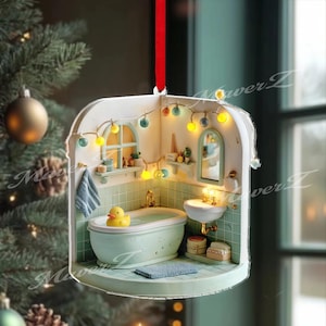 Könnte beinhalten: Miniatur-Badezimmer-Ornament mit rotem Band zum Aufhängen. Der Innenraum verfügt über eine Badewanne mit einer Gummiente, ein Waschbecken und ein kleines Fenster. Das Ornament ist mit Lichterketten und einem blau-weißen Farbschema verziert.