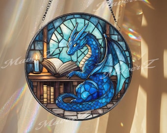 May include: Round stained glass window art featuring a blue dragon reading a book in a library setting. The dragon has detailed scales and wings. A lit candle and books are on a wooden shelf. The window is framed with a black metal chain.