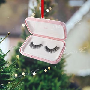 May include: A pink, rectangular case with a hinged lid, containing a pair of black false eyelashes. The case is suspended by a red ribbon. The word "hulu" is printed inside the case.