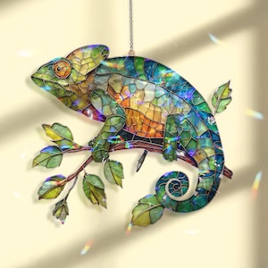 May include: A stained glass chameleon suncatcher, suspended by a chain. The chameleon, in shades of green, blue, orange, and yellow, is perched on a branch with green leaves. This decorative piece is designed to catch the light, creating a colourful display.