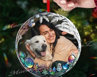 Op de afbeelding: Een ronde, heldere kerstbal met een foto van een vrouw en een hond. De ornament heeft een decoratieve zilveren filigraanrand en is versierd met kleurrijke edelstenen en een sneeuwpop. Een rood lint is bevestigd om op te hangen.