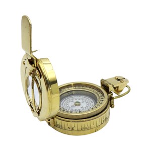 May include: A polished brass pocket compass with a hinged lid and a vertical sighting window. The circular dial features cardinal directions and degree markings. A small metal sight is attached to the side, and the outer casing displays engraved directional labels including NNE, NE, and ENE.