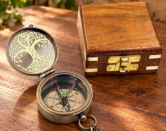 Puede incluir: Una brújula de bolsillo de latón con un diseño de árbol grabado en la tapa interior y una esfera magnética con puntos cardinales. La brújula viene acompañada de una caja de almacenamiento cuadrada de madera con bisagras de latón.