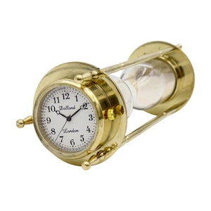 Può includere: Una clessidra color oro con un quadrante. Il quadrante ha numeri e lancette neri, con la scritta "Dollond London" stampata sul quadrante. La clessidra è realizzata in vetro e metallo color oro.