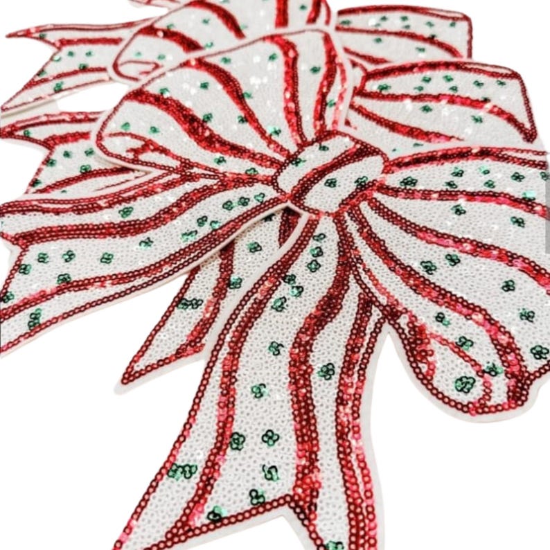 May include: Close-up of several decorative bows. The bows are white with red stripes and green accents. The bows are covered in sequins, adding a festive touch. These bows are perfect for holiday decorations.