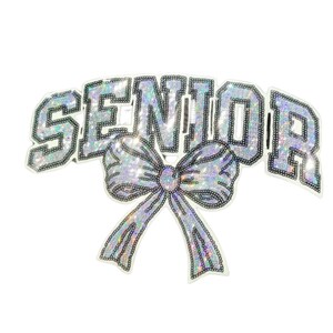 May include: A silver sequined "SENIOR" sash with a large bow. The text is outlined in black and filled with iridescent sequins. The bow is also silver and sequined, with black outlining.
