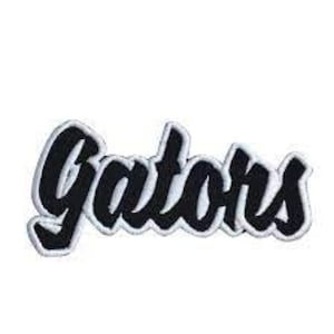 May include: A black and white embroidered patch with the word "Gators" in a script font. The letters are black with a white border, set against a white background. This patch is suitable for apparel and accessories.