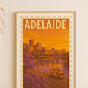 Puede incluir: Una impresión artística enmarcada que presenta una ilustración de estilo vintage de Adelaida, Australia. La obra de arte representa un paisaje urbano con un puente, un tranvía y el texto "ADELAIDE" en la parte superior, sobre un cielo cálido color atardecer.