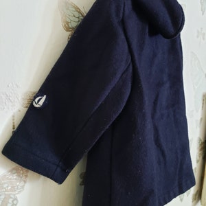 May include: A dark blue hooded jacket with a small white sailboat logo on the sleeve.