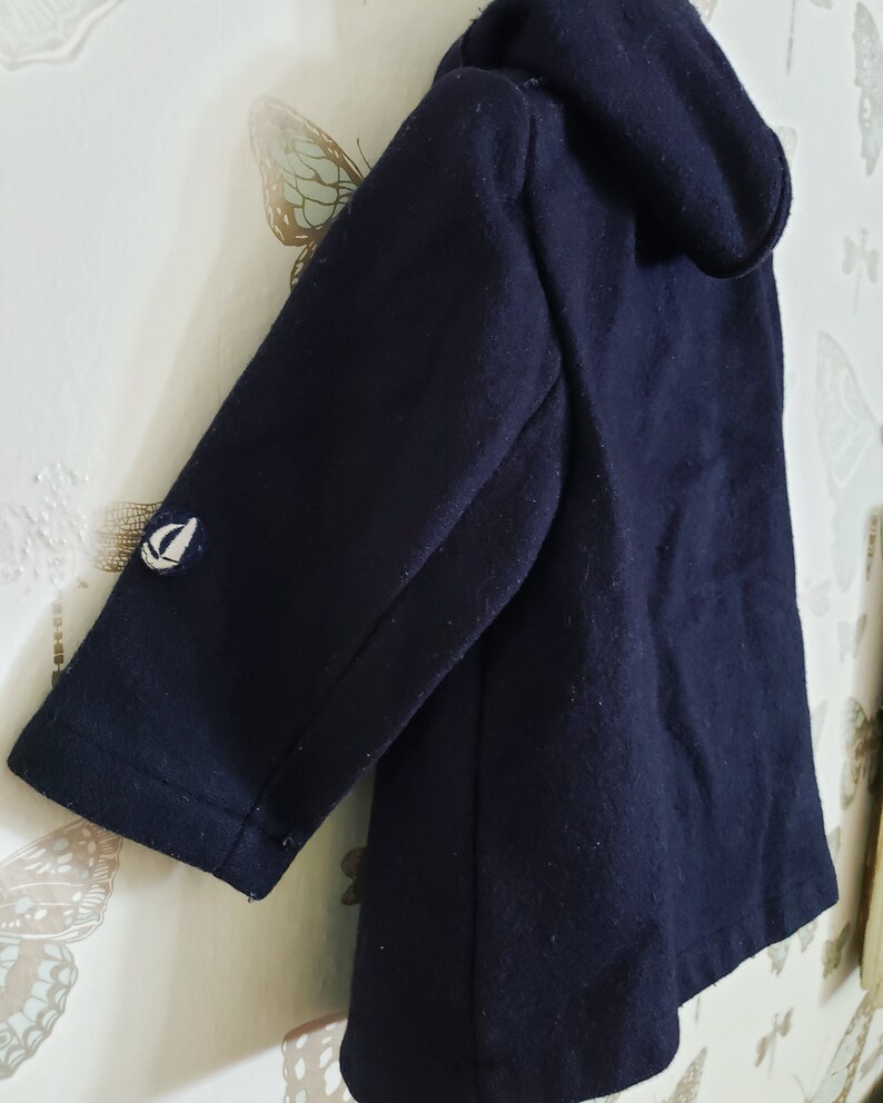 May include: A dark blue hooded jacket with a small white sailboat logo on the sleeve.