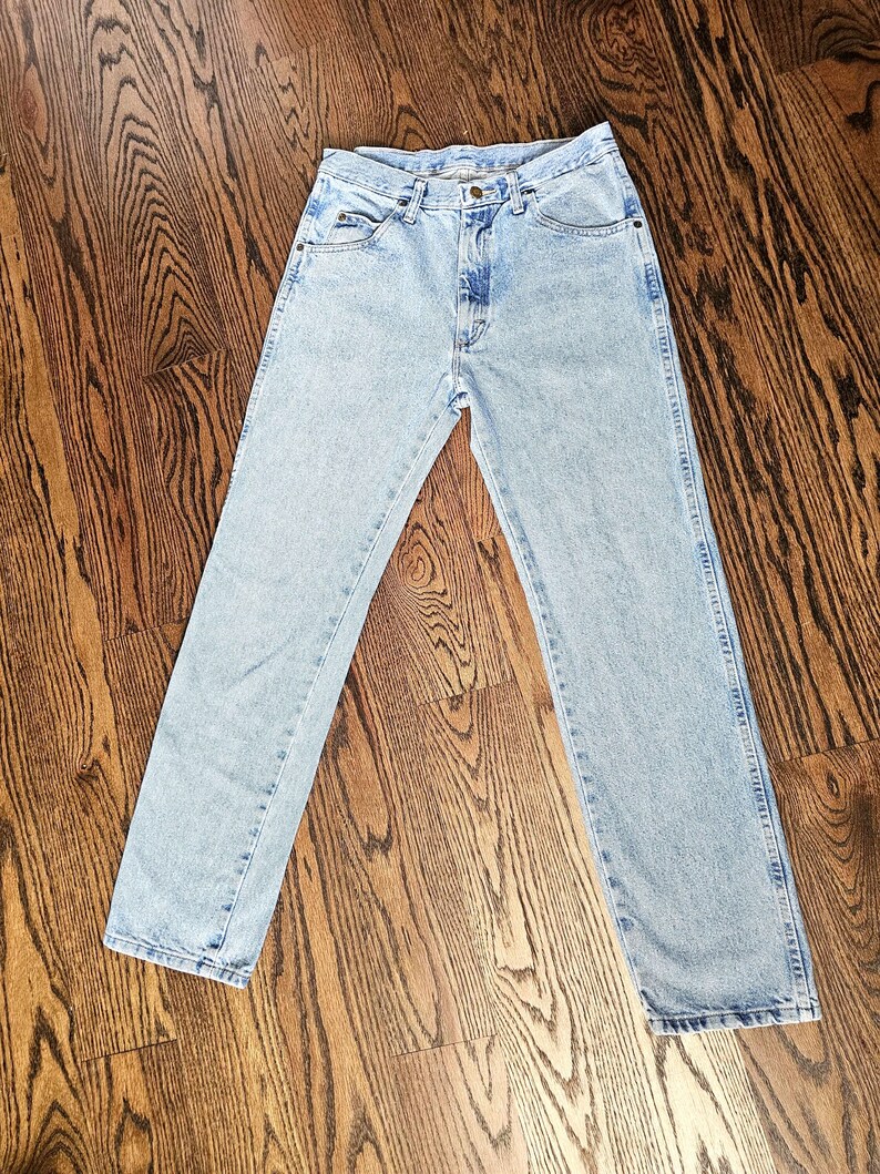 May include: Light blue denim jeans with a classic five-pocket design. The jeans have a straight leg cut and a faded wash, giving them a vintage look. The jeans are made of durable denim material.